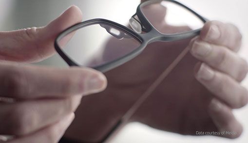 Hands holding a pair of prescription glasses, representing 3D printed consumer goods and electronics