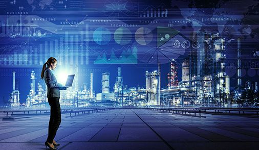 Female engineer standing in front of an industrial complex working on a laptop