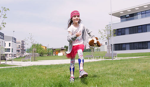 Little girl running in in a green field, with custom fitted 3D printed leg braces