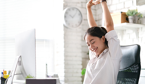 Woman smiling and stretching from an ergonomic chair