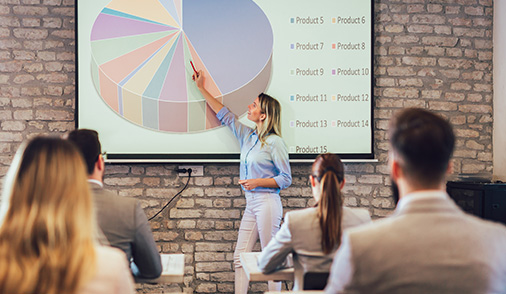 Woman presenting to a group using a large screen to highlight key points to the audience